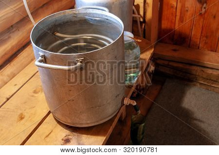 The Process Of Preparing Moonshine In A Village Bath In A Primitive Moonshine Distilling-apparatus. 