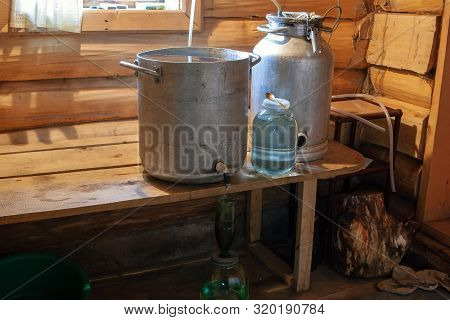 The Process Of Preparing Moonshine In A Village Bath In A Primitive Moonshine Distilling-apparatus.