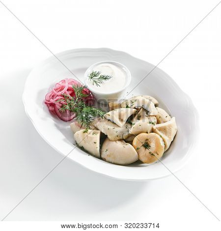 Pickles set with homemade pickled milk mushrooms, marinated red onion rings and sour cream on white restaurant plate isolated. Salted Lactarius resimus mushroom with oil and fresh chopped dill