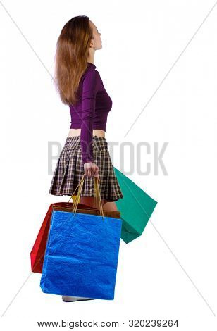 back view of woman in striped T-shirt with shopping bags . beautiful brunette girl in motion.   Isolated over white background. A fair-haired woman is walking sideways by waving bags.