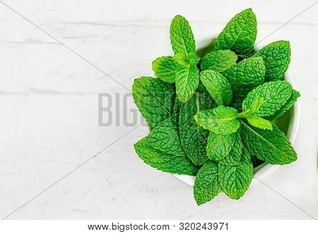 Peppermint Leaves On White Wooden  Background. Bunch Of Mint, Spearmint Leaves. Top View. Copyspace