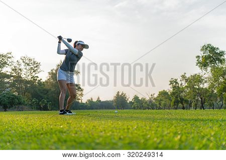 Healthy Sport. Asian Sporty Woman Golfer Player Doing Golf Swing Tee Off On The Green Evening Time, 