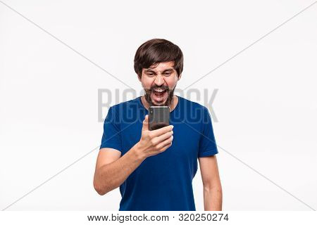 Displeased Handsome Brunet Man In A Blue Shirt With Beard And Mostaches Shocked Looking At The Scree