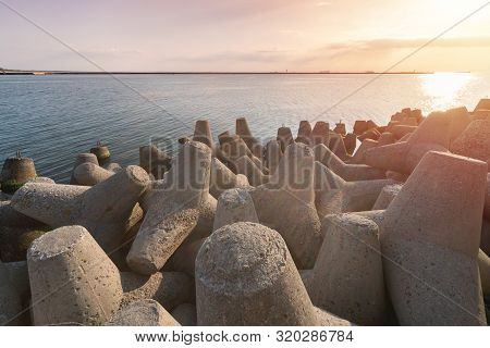 Tetrapod Breakwaters In Sea Water. Beautiful Sunset Seascape With Concrete Tetrapodes For Protect Co