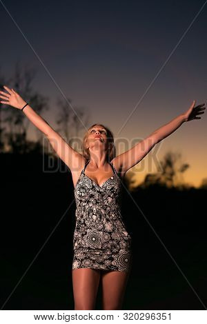 Woman On The Beach Dusk With Arms Raised