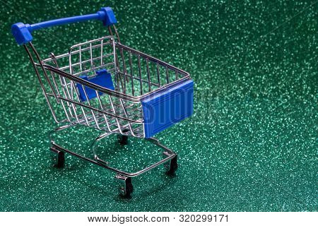 Shopping Trolley On A Shiny Green Background With Sparkles. Copy Space. Concept Festive Sale Online,