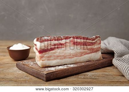 Board With Bacon And Salt On Wooden Table. Space For Text