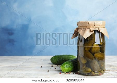 Jar With Pickled Cucumbers On White Wooden Table Against Blue Background, Space For Text
