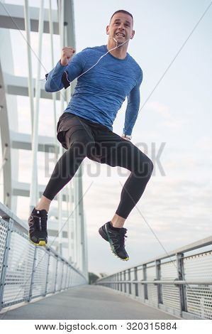 Sportsman Celebrating Successful Training With High Jump And A Raised Fist. Low Angle View- A Man In
