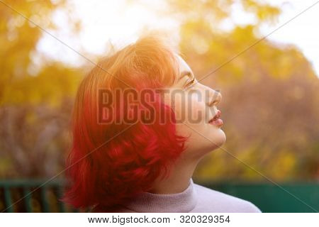 Beautiful Woman With Red Dyed Hair And Background Of Autumn Yellow Leaves.