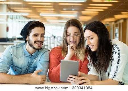 University Students Using Digital Tablet In University Library.
