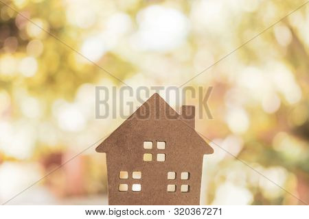 Closed Up Tiny Home Model On Floor Or Wood Board With Sunlight Green Bokeh Background. House Propert