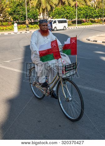 Salalah, Sultanat Of Oman - November 12, 2017:  Unknown Cyclist On A Bicycle With Flags On A Street 