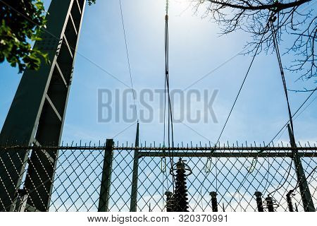 Low Angle View Of High Voltage French Power Lines Against Blue Sky Background At The Hydroelectric P