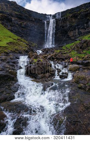 Tourist Standing At The Fossa Waterfall On Island Bordoy In The Faroe Islands, Denmark