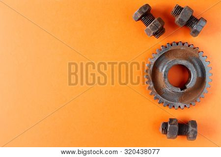 Rusty Bolts, Nuts And Gear Wheel Made Of Chocolate Isolated On Orange Background. Mechanic Gearing B