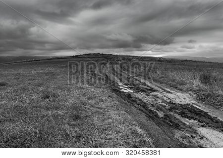 Dirt Road After Heavy Rain Leading To The Top Of The Hill, Stormclouds On The Dark Sky In Black And 