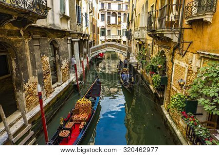 Venice, Italy - May 26, 2019: Unidentified People At Traditional Gondola In The Narrow Canal In Veni