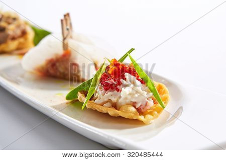 Taco with seafood assorti closeup. Mexican traditional dish. Wheat tortilla with sea food fillings on plate. Served delicious snacks. Appetizer composition isolated on white background