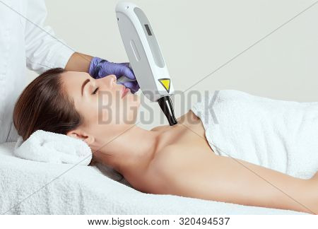 The Cosmetologist Is Making Carbon  Peeling Procedure On The Collarbone And Face In A Beauty Salon.