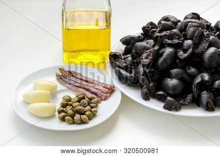 Ingredients For Tapenade: Pitted Black Olives On White Plate, Olive Oil In Glass Bottle, Three Clove