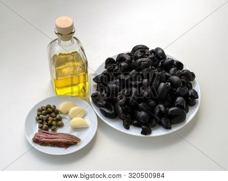 Ingredients For Cooking Tapenade: Pitted Black Olives On White Plate, Olive Oil In Glass Bottle, Thr