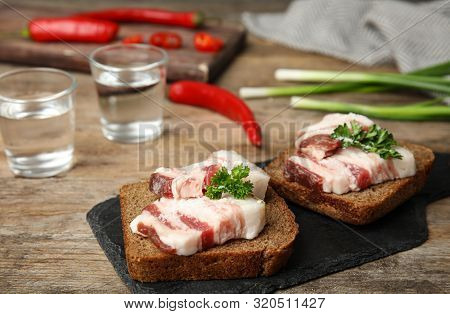 Board With Pork Fatback Sandwiches, Shots Of Vodka, Onion And Pepper On Wooden Table