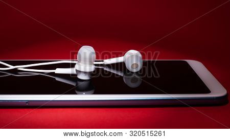 Concept: Listen To Music From The Phone.white Headphones Lying On The Smartphone