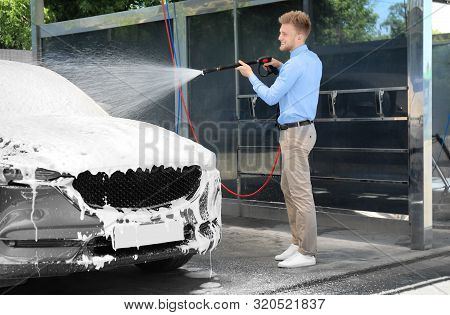 Businessman Cleaning Auto With High Pressure Water Jet At Self-service Car Wash