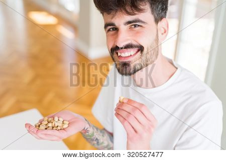 Young man eating pistachio, close up of hand with a bunch of hea