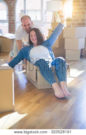 Funny and crazy couple having fun riding a cardboad box as a car, smiling happy and lauging at new home