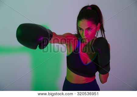 Picture of young gorgeous beautiful strong fitness woman boxer isolated with led flash lights make boxing exercises in gloves.