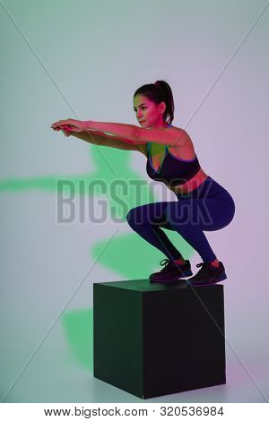 Image of young serious sports woman make exercise isolated with led flash lights.