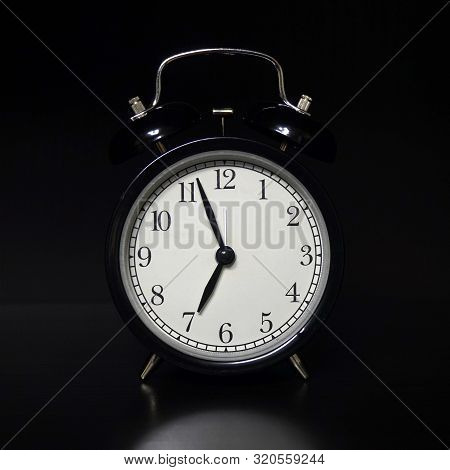 Classic Mechanical Alarm Clock On Dark Background. Low Key