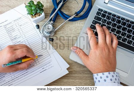 Working Environment, Desktop Or Scene Doctor Top View Or From Above. Doctor Hand Typing On The Compu