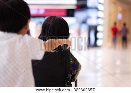Young Boy Pushing Great Grandmother In Wheelchair At Shopping Certer.