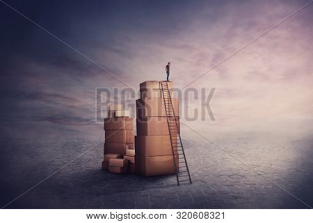 Surreal Scene As A Minuscule Man Wanderer Standing On A Stack Of Cardboard Boxes, Holding Hand To Fo