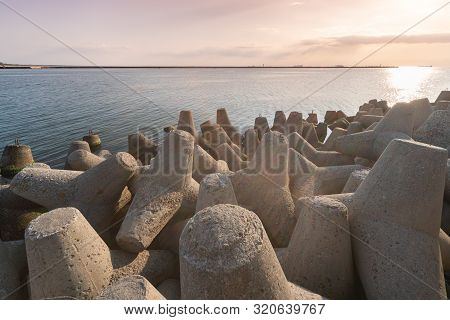Tetrapod Breakwaters In Sea Water. Beautiful Sunset Seascape With Concrete Tetrapodes For Protect Co