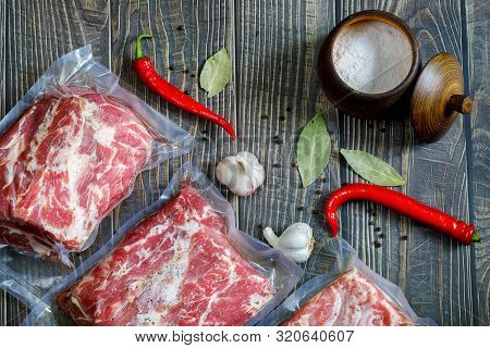 The Meat Is Vacuum Packed With Spices And Nitrite Salt On Wooden Background.