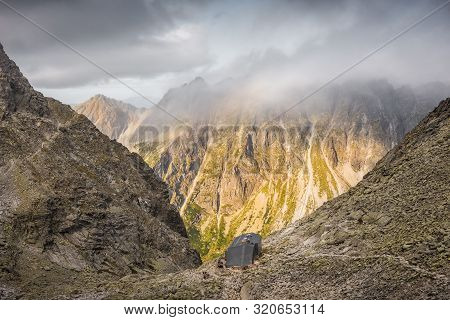 Mountain Landscape With Cottage Under Rysy Peak As Seen From Sedlo Vaha At Sunrise With Golden Light