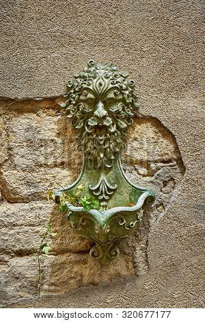Roman Fountain With Green Plant On A Stone Wall At Barjac Gard Occitanie France
