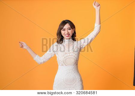 Young Pretty Asian Woman Smiling With Energetic Movement Studio Shot Isolatede On Colorful Yellow Ba