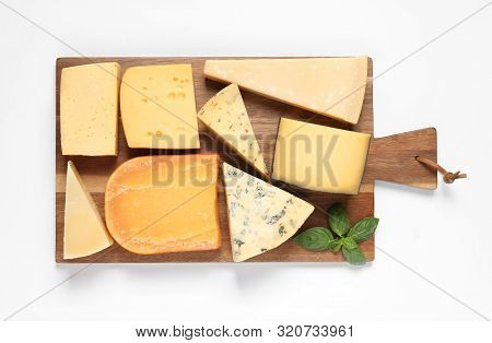 Wooden Board With Different Kinds Of Cheese And Basil On White Background, Top View
