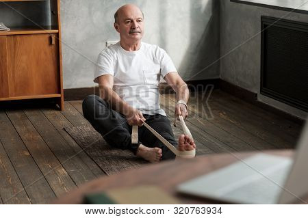 Senior Hispanic Man Sitting In Janushirshasana Using Belt