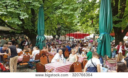 Munich, Germany - 27 July, 2019: People Eating And Drinking In A Garden In The City Center. The City