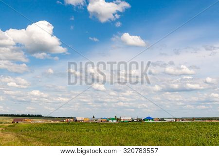 Beautiful White Clouds In The Blue Sky Over The Russian Village. Summer Afternoon Over A Russian Vil