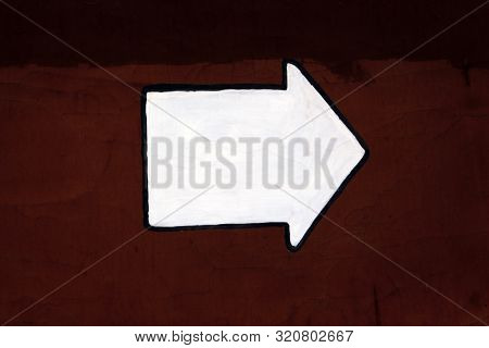 White Arrow Painted On Dark Red Concrete Wall