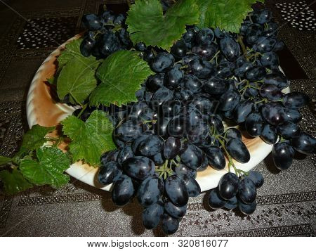 A Large Bunch Of Grapes Lies On A Large One.