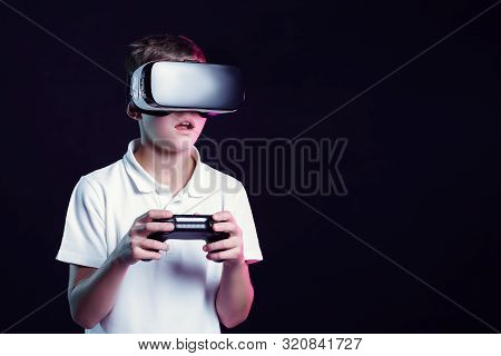 Excited Kid In White T-shirt And Virtual Reality Headset Standing Bending Forward Playing With Joyst