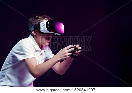 Side View Of Excited Kid In White T-shirt And Virtual Reality Headset Standing Bending Forward Playi